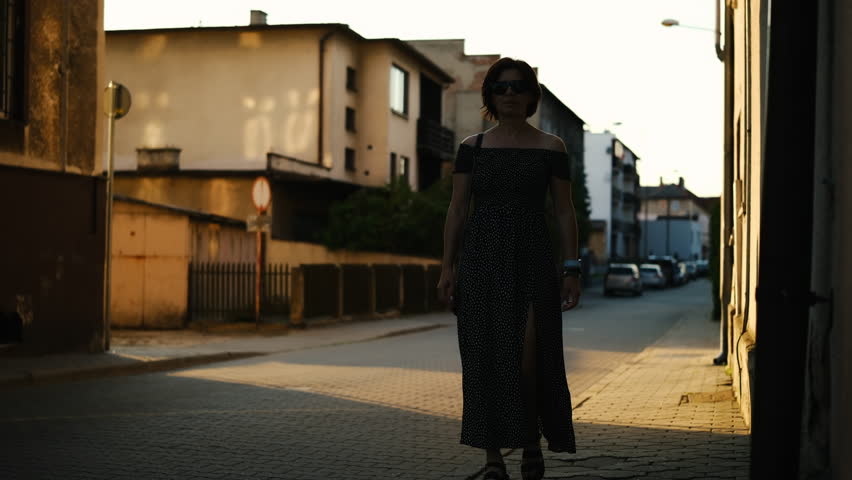 Attractive Young Woman Walks In The Historical Part Of A European City, Stylish Girl In Sunglasses Strolls At Sunset