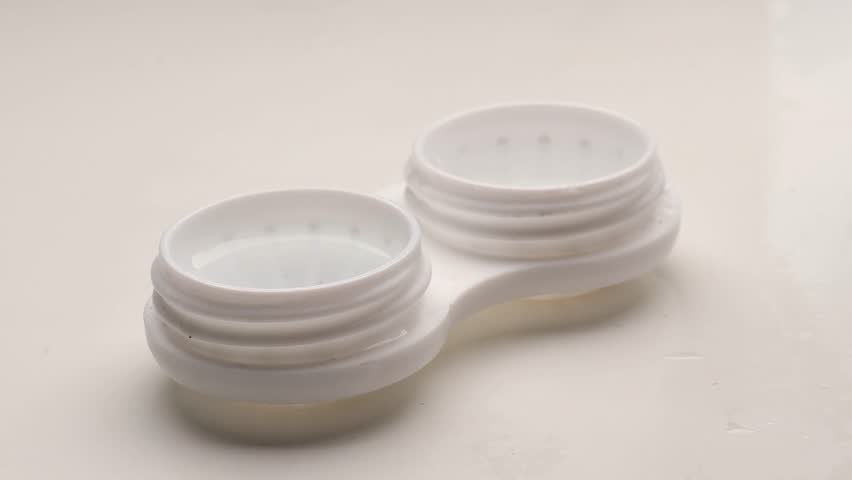 close-up of contact lens solution being poured into a white lens case, concept of eye care, vision correction, and ophthalmology