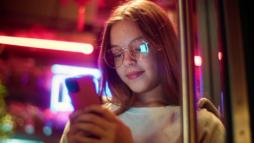 Caucasian Asian girl teenager junior use mobile phone in city schoolgirl kid chat social media daughter typing cellphone child Internet night The inscription noodle in Chinese. Translation: 'noodle'. 