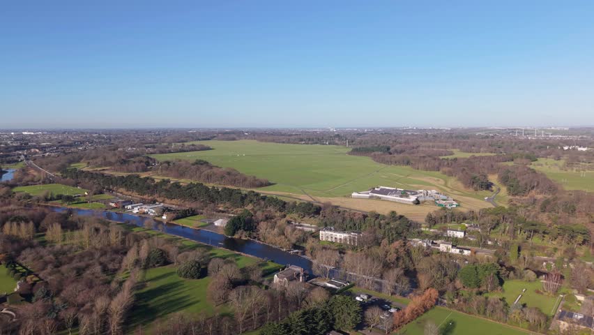 Phoenix park, dublin, showing vast green fields, trees, and a river, aerial view