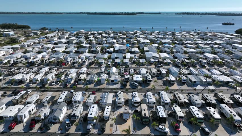 RV Park and travel trailer campground in Bradenton, Florida. Aerial lateral wide shot. Dense populated places. Sunny day in America. Manatee River in background.