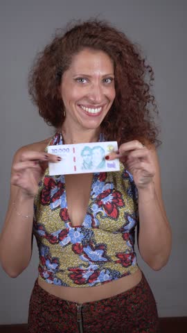 Happy Woman Displaying Argentinean Currency with a Bright Smile.