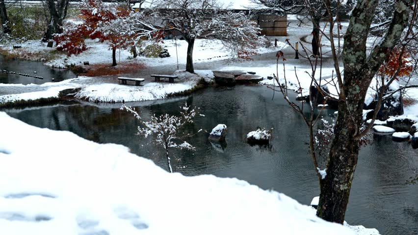 A serene winter scene in Shirakawa-go, Japan, featuring a snow-covered garden and tranquil lake.