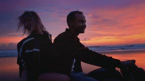 Romantic couple on motorcycle rides along a sandy black beach in Bali. Man and woman at sunset drive bike. Female and male make an adventure, road trip. Twilight and the blue hour. - Powered by Shutterstock - Get 15% off with code: PIKWIZARD15