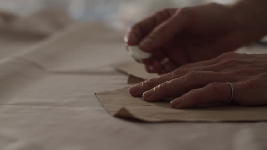 Unrecognizable woman tailor transferring pattern on fabric