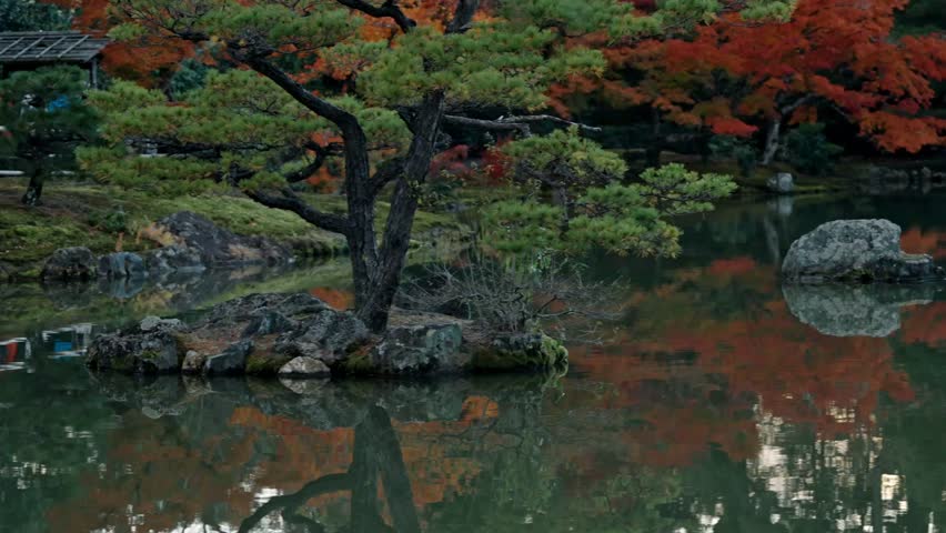 The iconic Golden Pavilion, Kinkaku-ji, reflects beautifully on the tranquil lake surrounded by the rich, vibrant colors of autumn foliage in Kyoto.