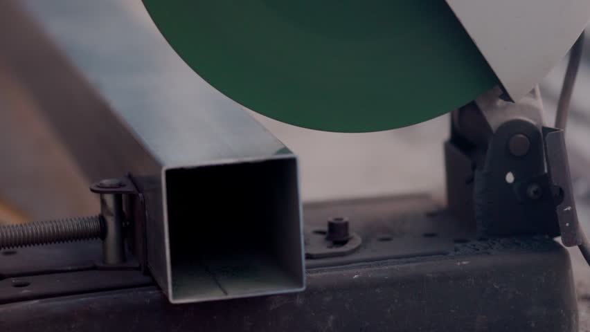 Worker cutting square steel pipe in constuction site.