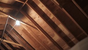 Exposed wooden roof framing with a single lightbulb illuminating an unfinished attic. - Powered by Shutterstock - Get 15% off with code: PIKWIZARD15