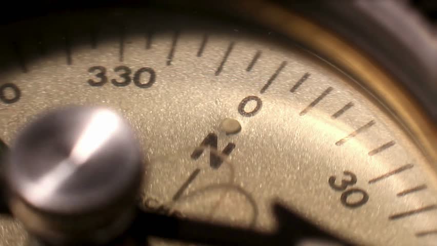 Closeup on a compass pointing direction. Old compass. Macro shot, shallow focus. Travel, geography, navigation, tourism and exploration concept background. Closeup of compass navigation tool.
