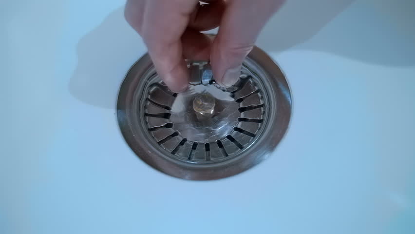 A man's hand opens the drain plug in a white round sink and water swirls into the drain. Closeup. Macro. Slow mo, slow motion, high speed camera, 250fps