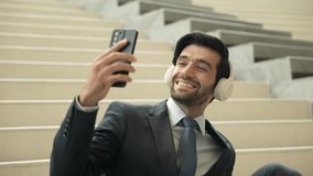 Smiling business man listening music while looking at mobile phone. Project manager holding phone while enjoy hip-hop song at stairs. Caucasian leader listen relax sound while plan project. Exultant. - Powered by Shutterstock - Get 15% off with code: PIKWIZARD15