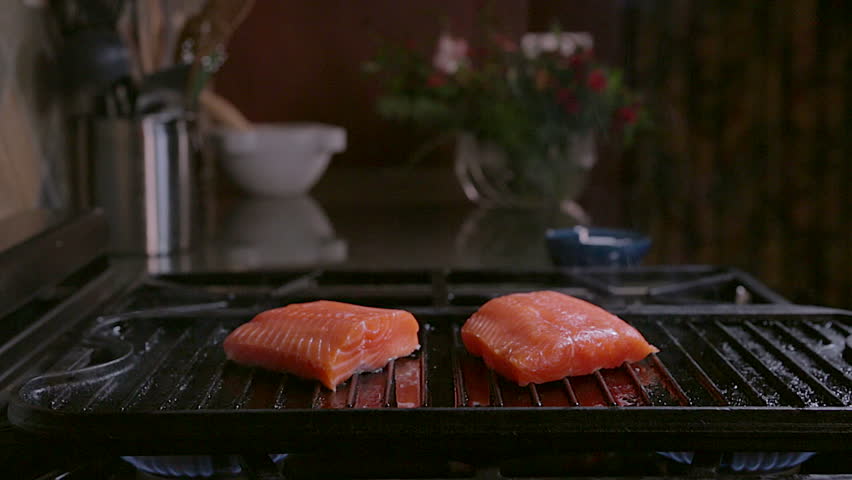 Man salting and grilling fresh salmon, pan in on grill
