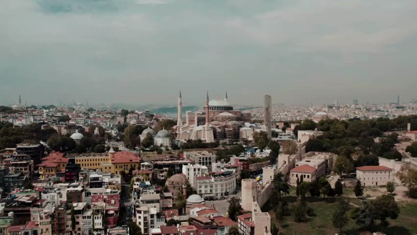 Panoramic perspective of Istanbul highlights famous landmarks, bustling streets filled with vibrant architecture, and serene parks. Late afternoon light enhances cityscape beauty from above.