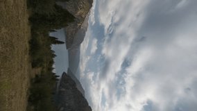 Lake in mountain gorge timelapse. Vertical video. Autumn landscape, yellowing trees and rocky mountains. Cloudy sky with occasional voids in clouds. Amazing cinematic video for background, ecology - Powered by Shutterstock - Get 15% off with code: PIKWIZARD15