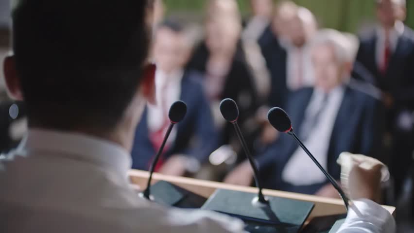 A male politician confidently delivering a speech at a podium, addressing an audience. A powerful moment symbolizing leadership, governance, public speaking, and political influence in a formal 