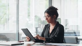 Smiling latina young professional business woman looking at pc device computer screen. Indian female businesswoman specialist holding digital tablet, using tab pad financial app at work in office - Powered by Shutterstock - Get 15% off with code: PIKWIZARD15