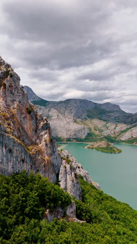 Unapproachable grey bare rocks with a lake among them. Splendid scenery of a national park in Leon, Spain, Europe under overcast sky. Vertical video.