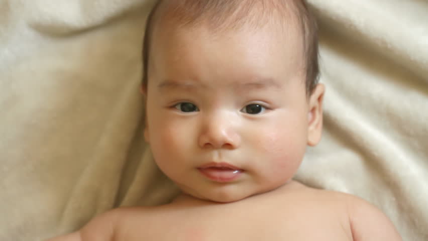 Close up of a happy three-month old baby boy on a soft blanket.