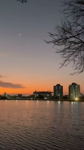Beautiful sunset over the heart-shaped reservoir at Prince of Songkla University, Songkhla, Thailand. Twilight sky, crescent moon, and water reflection create a peaceful scene.