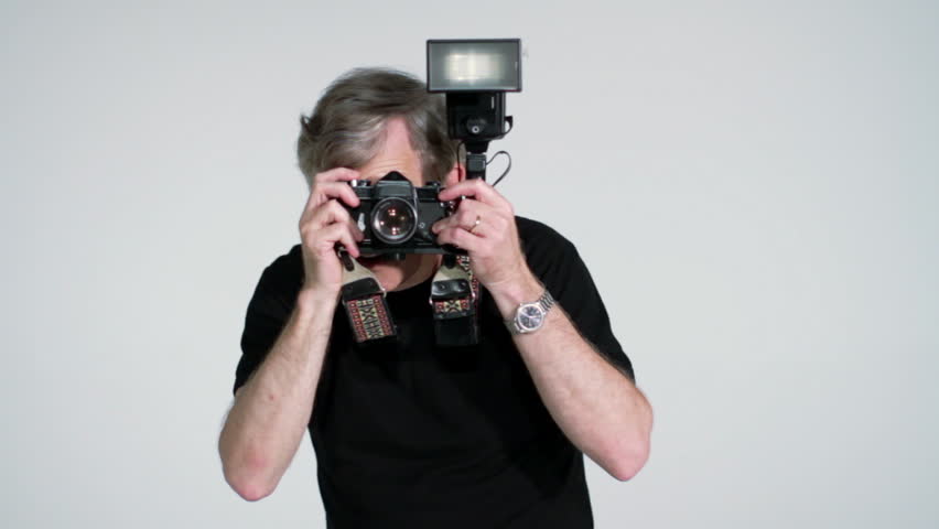 Photographer directing while taking pictures in studio with SLR and flash.