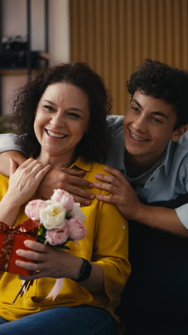 Teenage son hugging his mother, celebrating her birthday, showing family care
