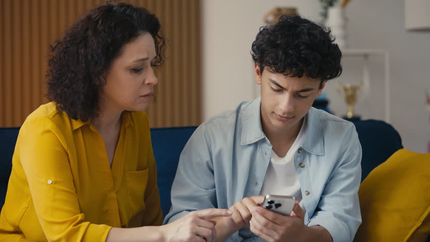 Teen son helping his mother with a new phone app, fixing gadget issues together