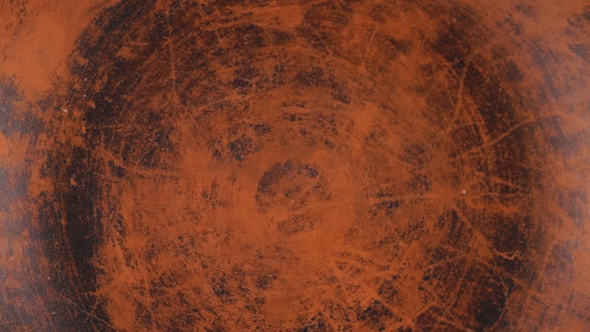 Chickpea seeds are poured into a brown ceramic bowl on a wooden oak board background. Top view. Slow motion.