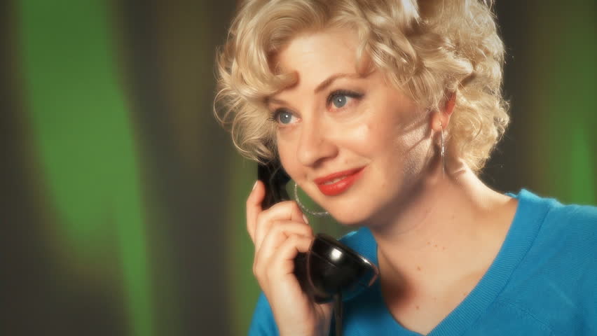 Blonde girl in a turquoise dress picks up phone and listens to call. Close up,