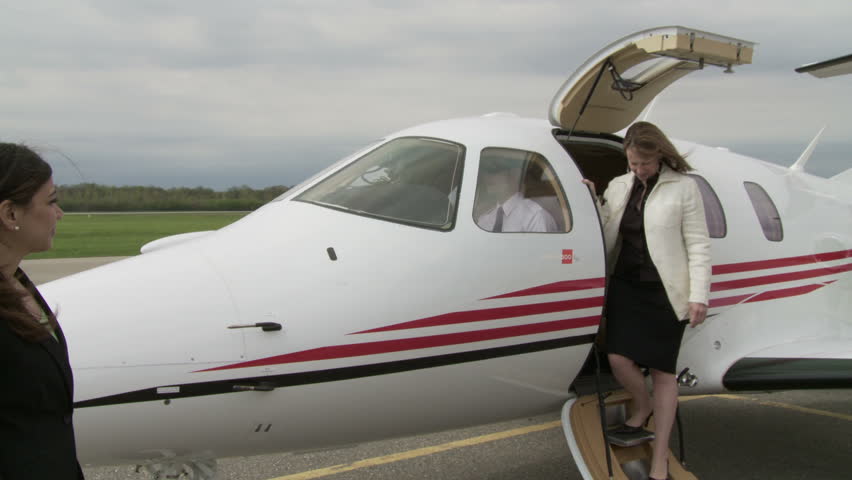 Executive woman gets out of a private jet and is welcomed by a woman at the