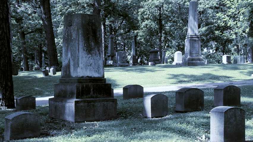 Beautiful, sad woman dressed in white walks through a cemetery. Wide shot,