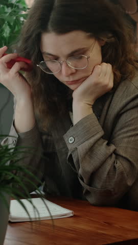 Vertical video. Remote work. Upset and disappointed freelance employee listens to voice message with edits and feedback from client.