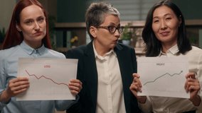 Confused Caucasian businesswoman leader choice diversity workers holding two graphics profit financial growth crisis chart investment loss money Asian women business office diagram indoors statistics - Powered by Shutterstock - Get 15% off with code: PIKWIZARD15