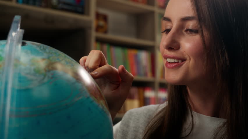 Caucasian woman spinning globe model earth geography lesson study learning choosing country travel tour trip dreaming female girl businesswoman vacation business student tourist teacher indoor library