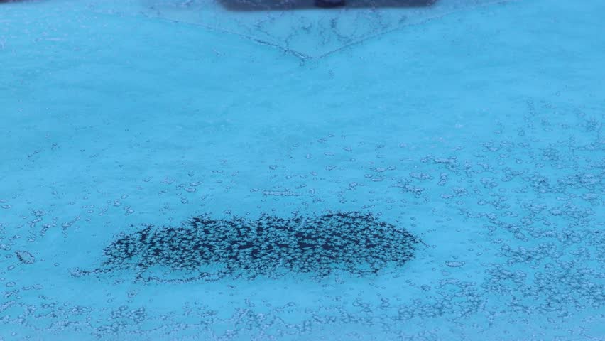 Frost gradually melting on a car rear window