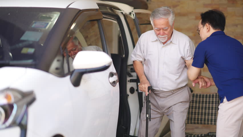 Asian man caregiver or taxi driver helping senior man patient get in the car to get to medical appointments or healthcare therapy sessions at hospital. Assisted elderly patient transportation services