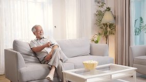 Happy Asian senior man watching movie using remote control change change on smart TV in living room. Elderly man enjoy leisure activity hobby indoor lifestyle at home. Retired people mental healthcare - Powered by Shutterstock - Get 15% off with code: PIKWIZARD15