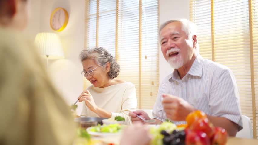 Happy Asian family senior parent and adult child celebration holiday  dinner party at home. Couple enjoy weekend activity lifestyle meeting cooking, eating and talking with elderly father and mother