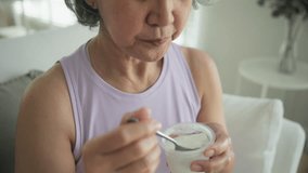 Asia adult people middle age happy old woman eat greek yogurt cup weight loss protein gut health care diet detox sit at home sofa elder aging asian aged female. Fresh medical food relief meal enjoy. - Powered by Shutterstock - Get 15% off with code: PIKWIZARD15