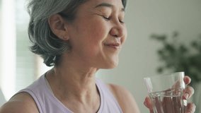 Asia adult people middle age happy old woman smile look at camera drink water stay hydrated reduce hot flash dry skin health care sit at home sofa elder aging asian aged female. Medical food relief. - Powered by Shutterstock - Get 15% off with code: PIKWIZARD15