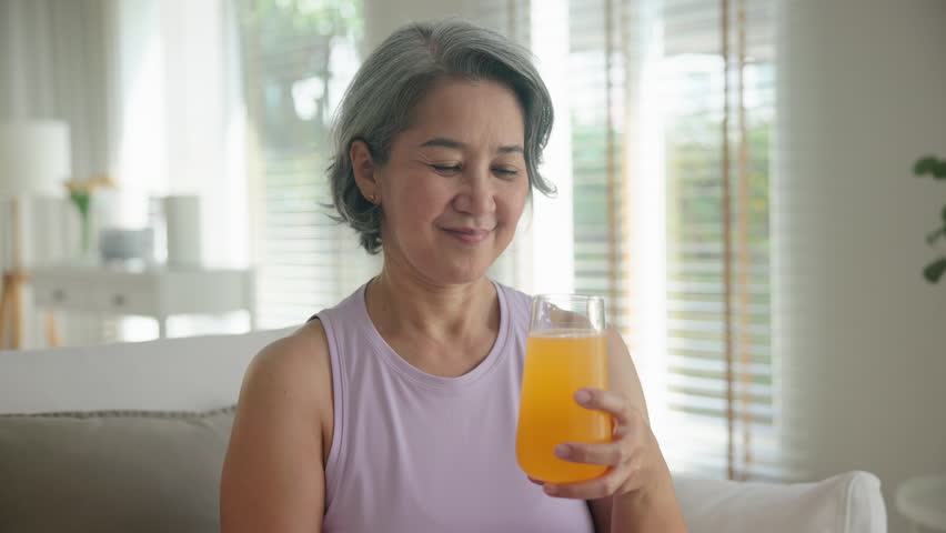 Asia adult people middle age happy old woman smile drink vitamin d c e k zinc water pill reduce hot flash dry skin health care sit at home sofa elder aging asian aged female. Take diet food relief