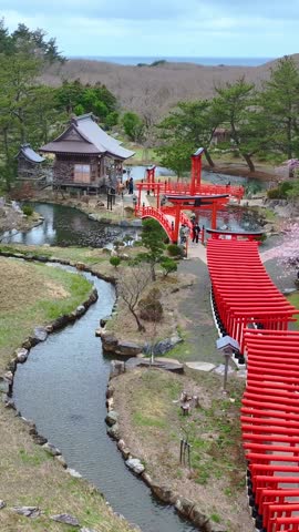 vertical drone shot of red torii gates in Takayama Inari shrine in Tsugaru, Aomori, zen Japanese landscape in spring, Japanese culture and shinto religion