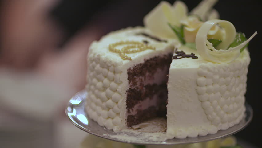 A close-up of a beautifully decorated wedding cake being sliced on a cake stand.