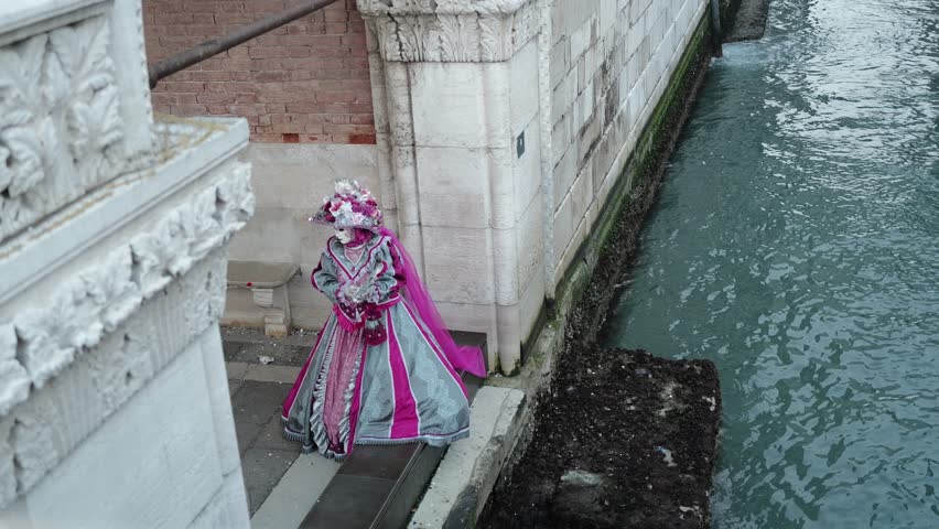 Venice, Italy - People dressed in carnival masks are photographed by tourists in the scenery of the ancient Venetian palaces