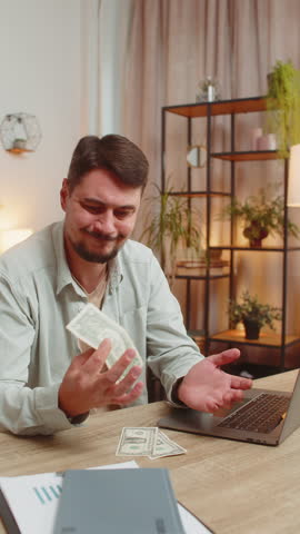 Caucasian man freelancer counting dollar cash insufficient amount of money. Financial crisis. Bankruptcy. Poverty and destitution. Upset businessman with laptop sitting at home office table. Vertical.