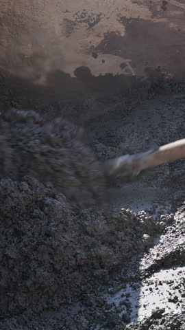 Workers are mixing and pouring concrete at a construction site, focusing on a smooth surface preparation.