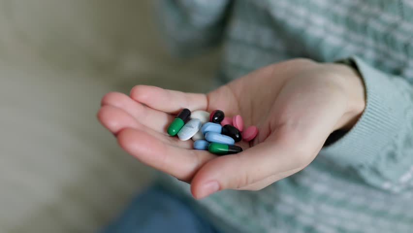 A woman hand take pills from the palm of his hand to take painkillers, medicines, vitamins or antibiotics. Close up. unrecognizable. At home. Indoor. Tablets, medicines