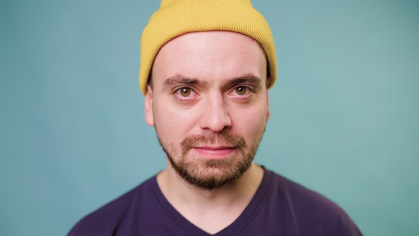 A studio shot of a screaming male, his expression one of fury and rage as he looks directly at the camera and shouts in a fit of emotion. studio shot on the blue background