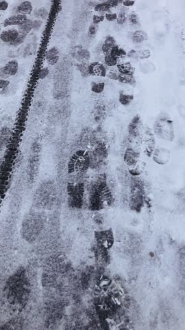 Footprints in the first snow on the sidewalk. The beginning of winter. Vertical format.