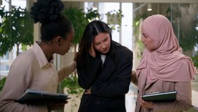 Multiracial girls in office smiling friendly conversation laughing women business partners colleagues three diverse businesswomen Asian Muslim African talk discuss together feel headache pain problem - Powered by Shutterstock - Get 15% off with code: PIKWIZARD15