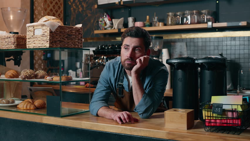 Frustrated Caucasian bartender man staff guy waiting clients in coffee shop bored employer working small business owner feeling stress cafeteria upset male barista no customers problem cafe difficulty